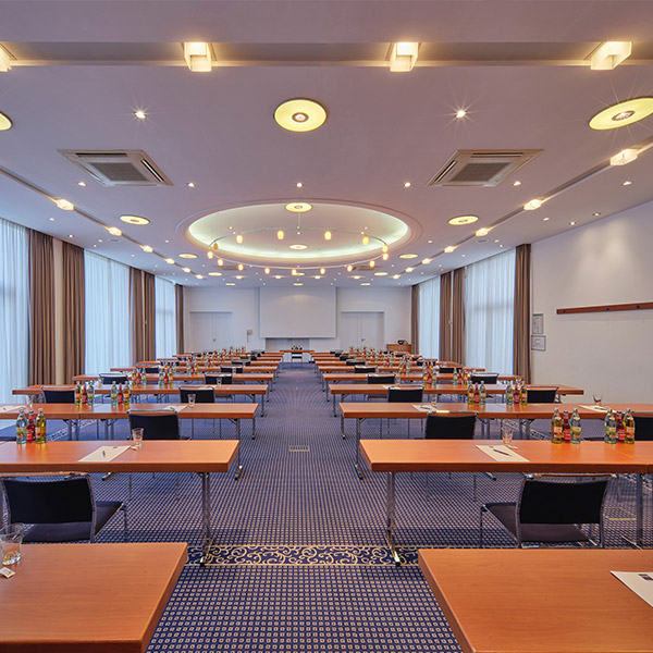 Großer Konferenzsaal mit vielen Tischen in Schulungsanordnung und stilvoller Deckengestaltung