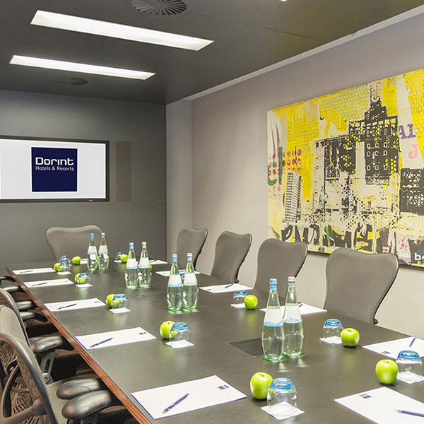 Moderner Boardroom mit grauem Konferenztisch, gelbem Wandkunstwerk und Dorint-Bildschirm