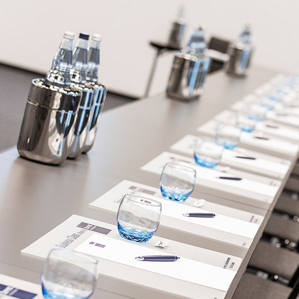 Detailaufnahme eines eleganten Konferenztisches mit blauen Gläsern und Wasserkrügen
