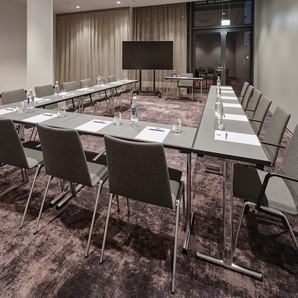 Moderner Konferenzraum mit U-förmiger Tischanordnung und grauen Stühlen