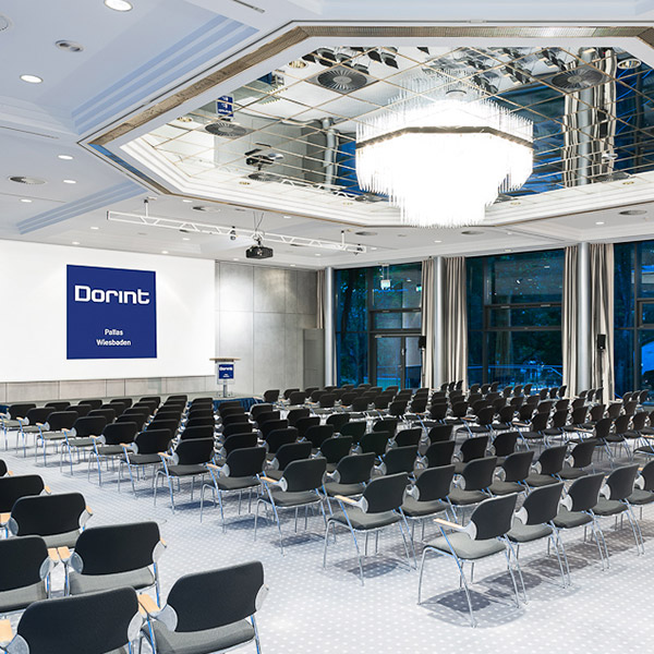Moderner Konferenzraum mit vielen Stuhlreihen, einem Podium und einem großen Kronleuchter