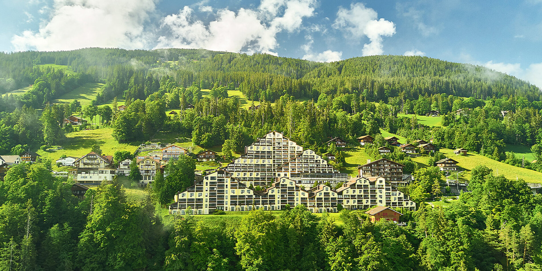 Großes Terrassenhotel im Pyramidenstil, eingebettet in grüne Hügellandschaft und Wälder