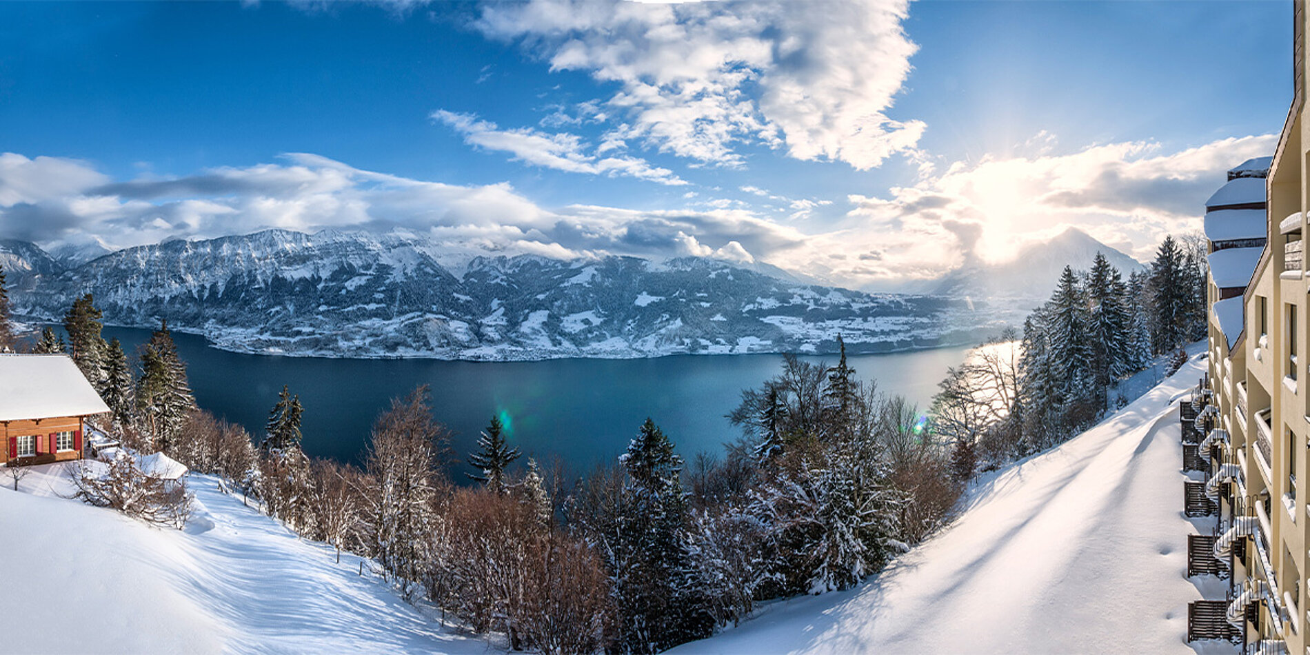 Winterlandschaft am Thunersee mit verschneiten Bergen und Hotel