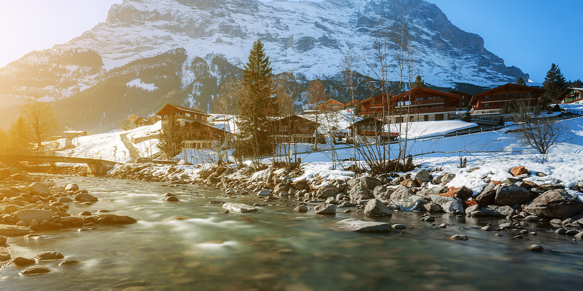 Bergfluss in Grindelwald mit verschneiten Häusern und Bergen