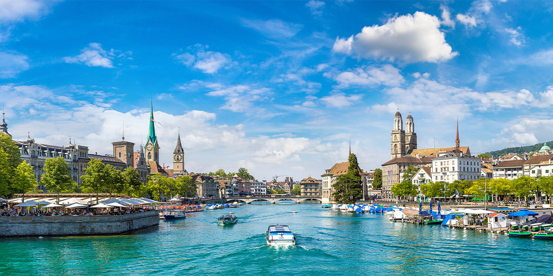 Panorama von Zürich am Fluss Limmat mit historischen Gebäuden und Booten unter blauem Himmel